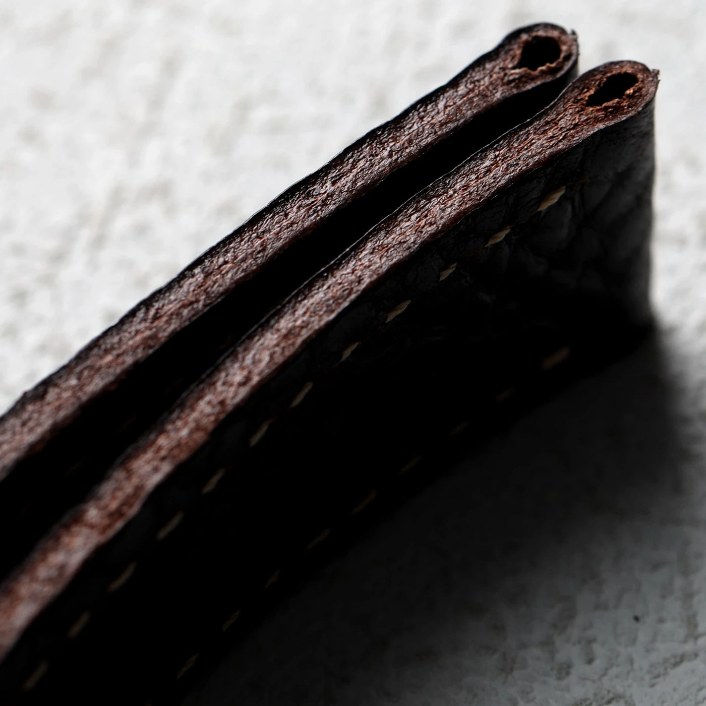 Close-up of a dark brown leather wallet on a textured surface