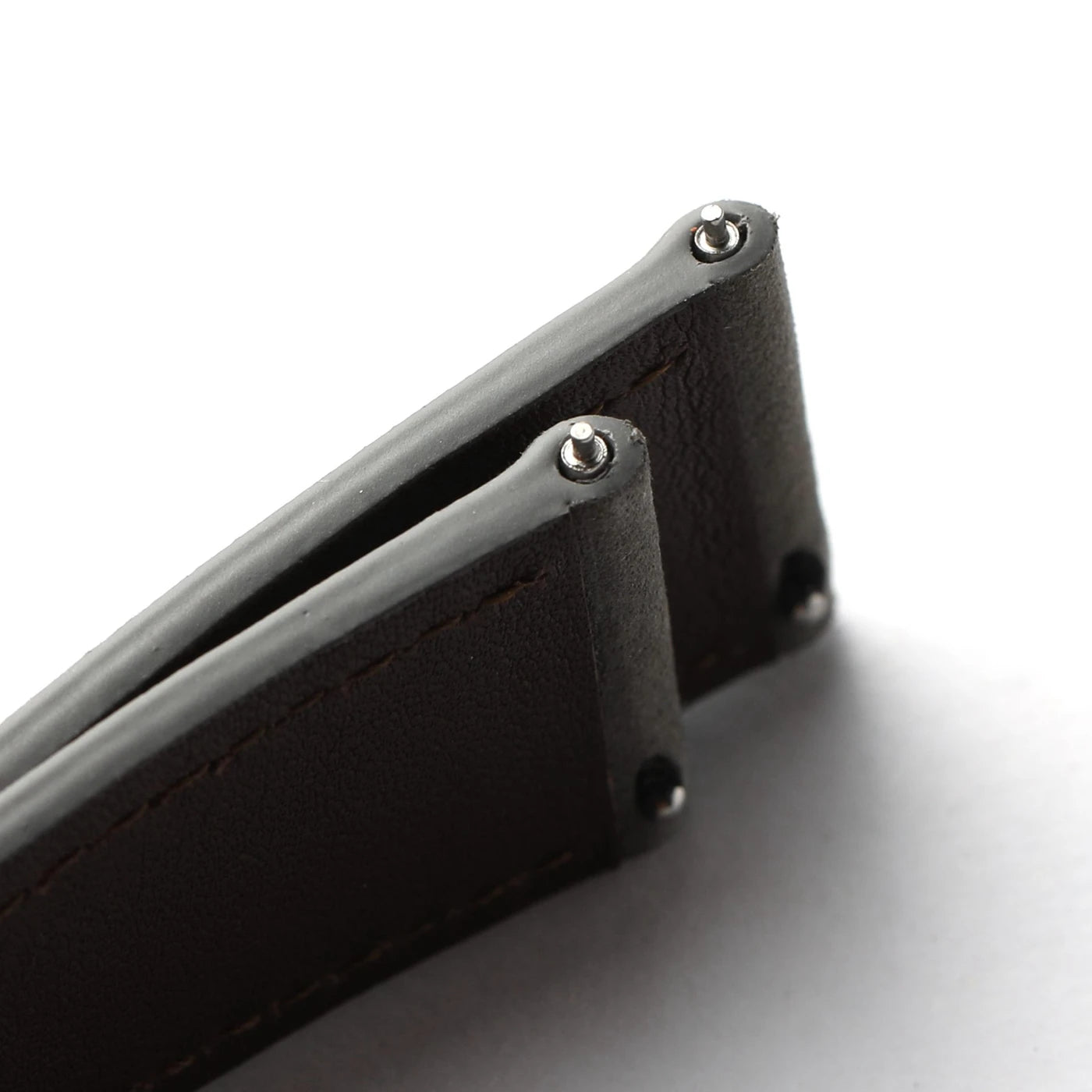 Close-up of a dark brown leather watch strap with silver-tone metal rivets and stitching, set against a plain white background.