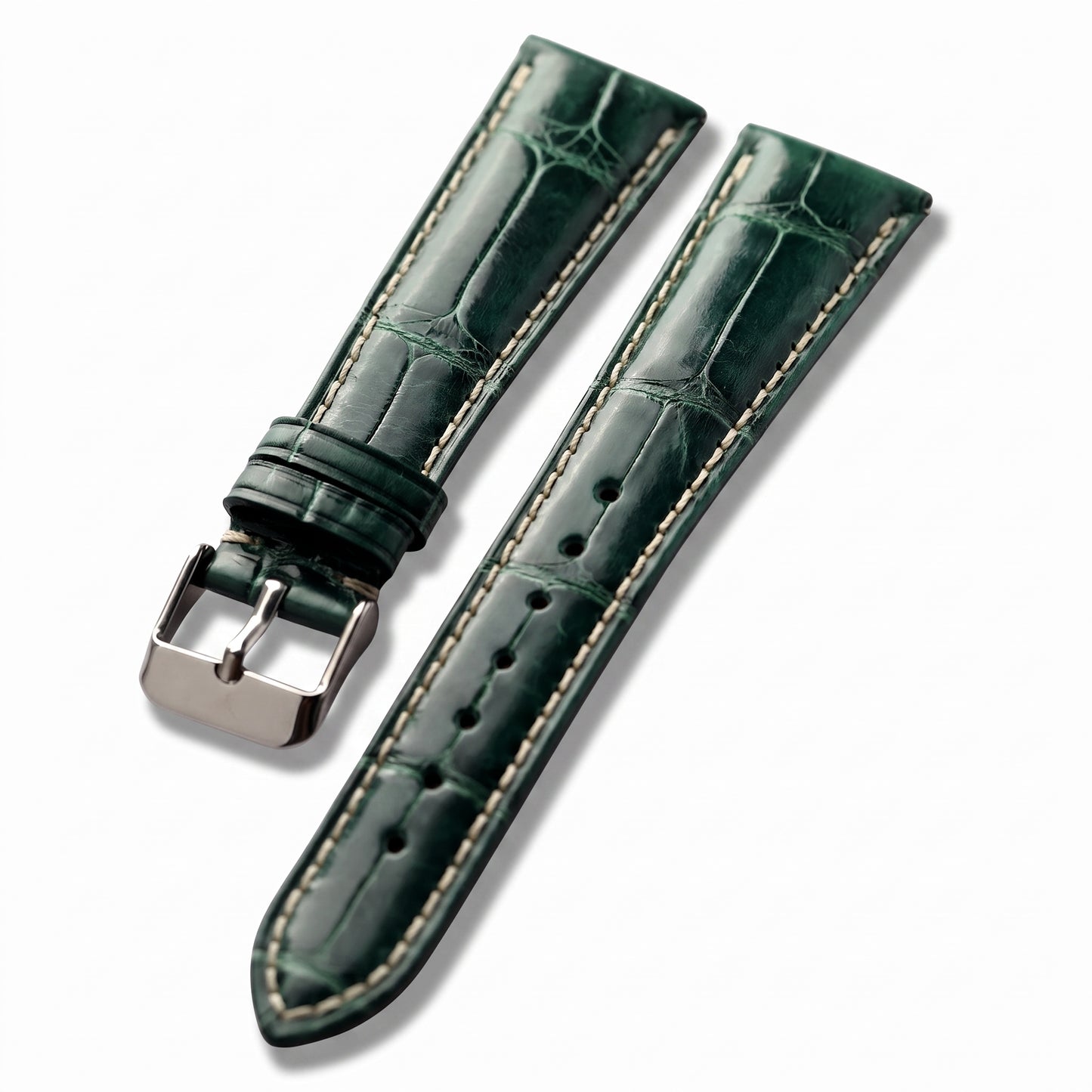A dark green alligator leather watch strap with light beige contrast stitching and a polished silver-tone buckle, shown on a clean white background.