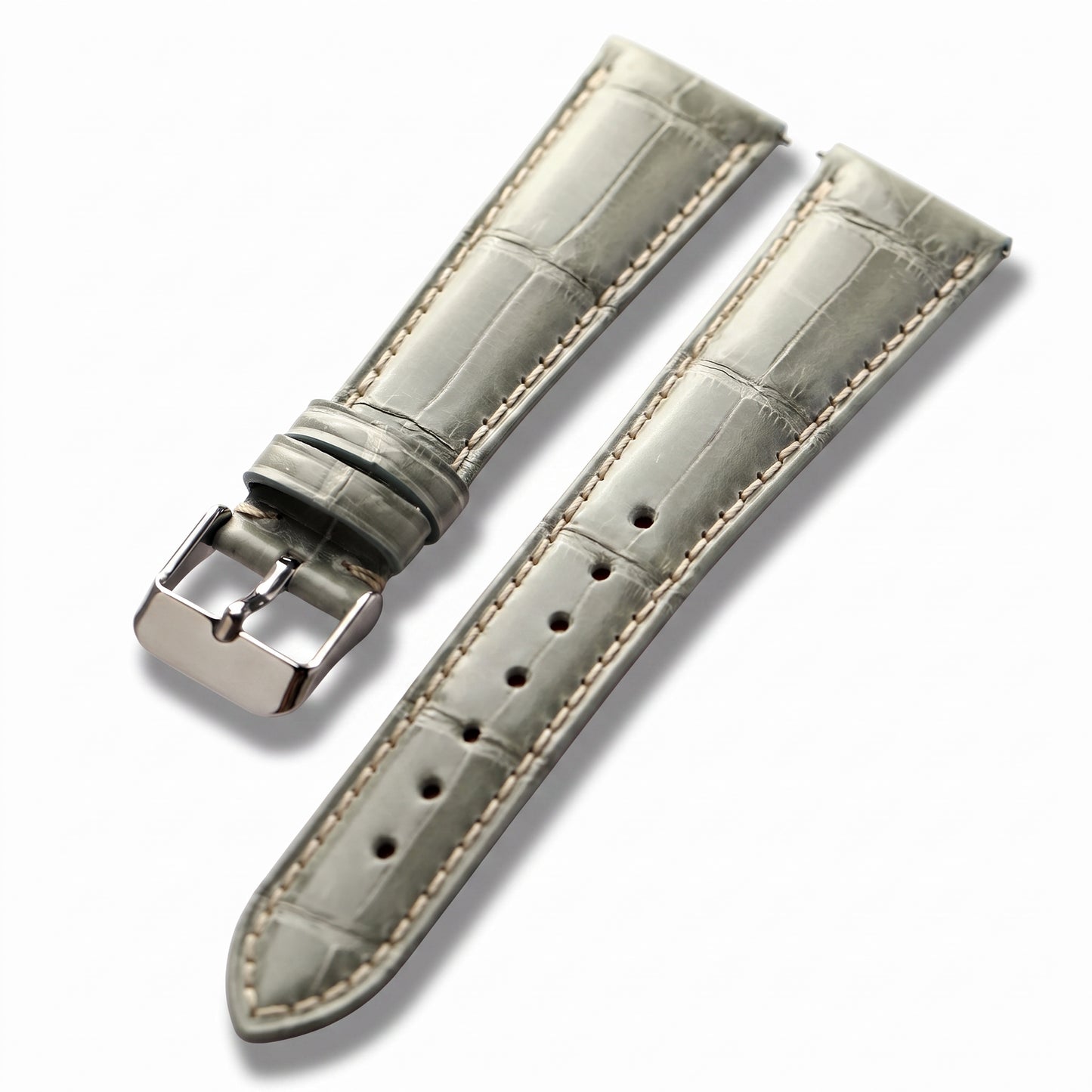 A light gray alligator leather watch strap with cream-colored stitching and a polished silver-tone buckle, displayed on a clean white background.
