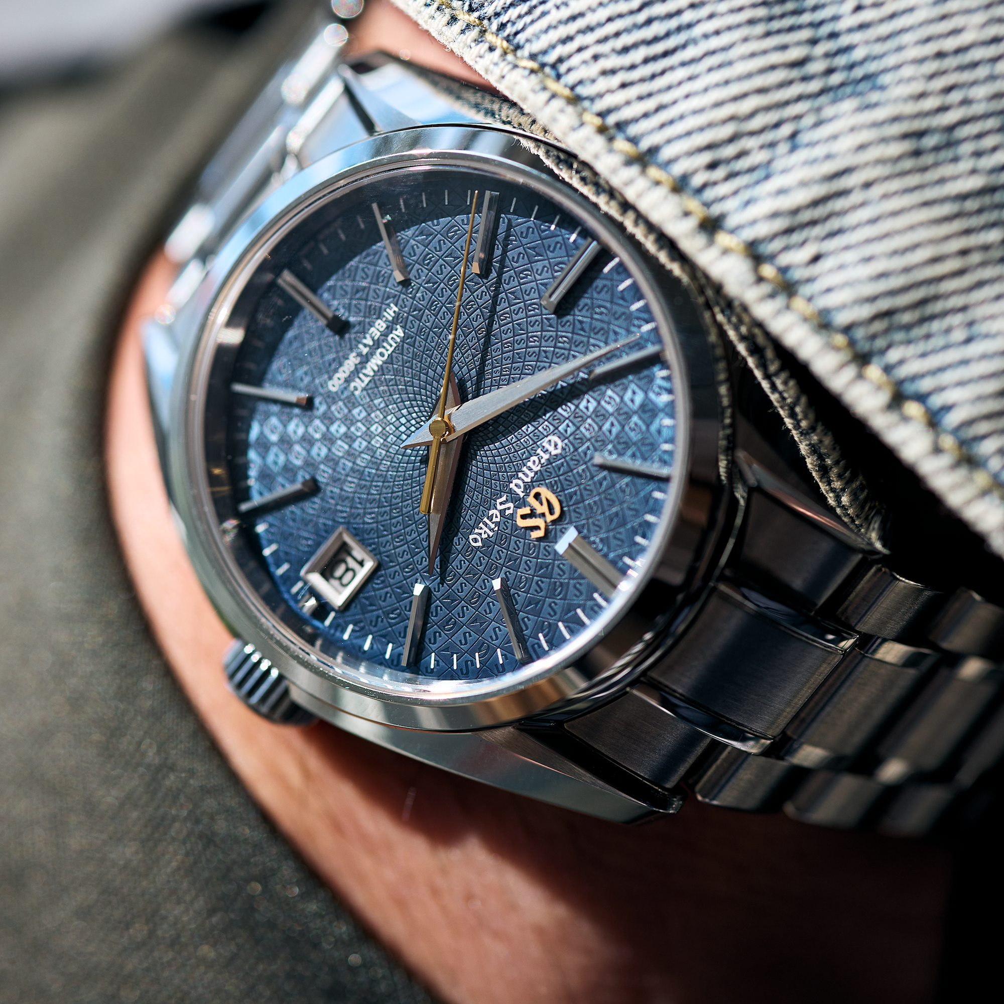 Close-up of a watch with a blue face and black strap on a person's wrist.