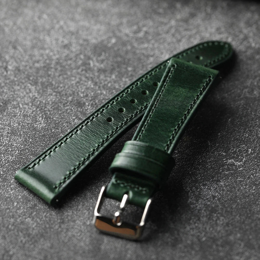 Green leather watch strap on a gray textured background