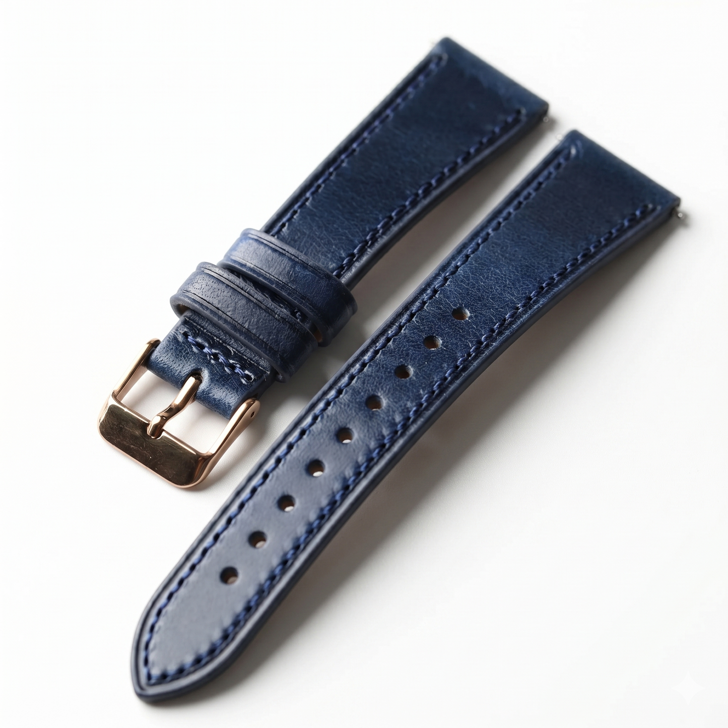 Blue leather watch strap with rose gold buckle on a white background