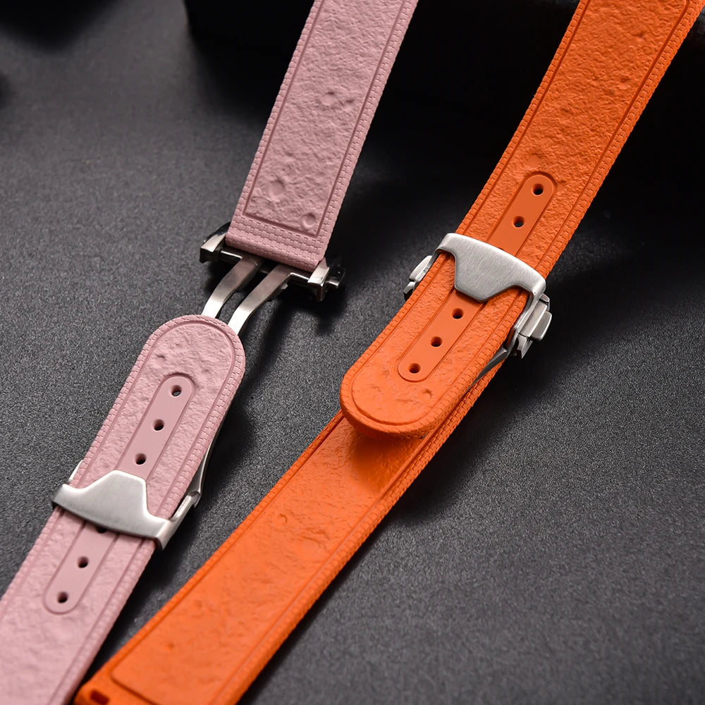 Pink and orange leather watch straps with silver buckles on a dark background