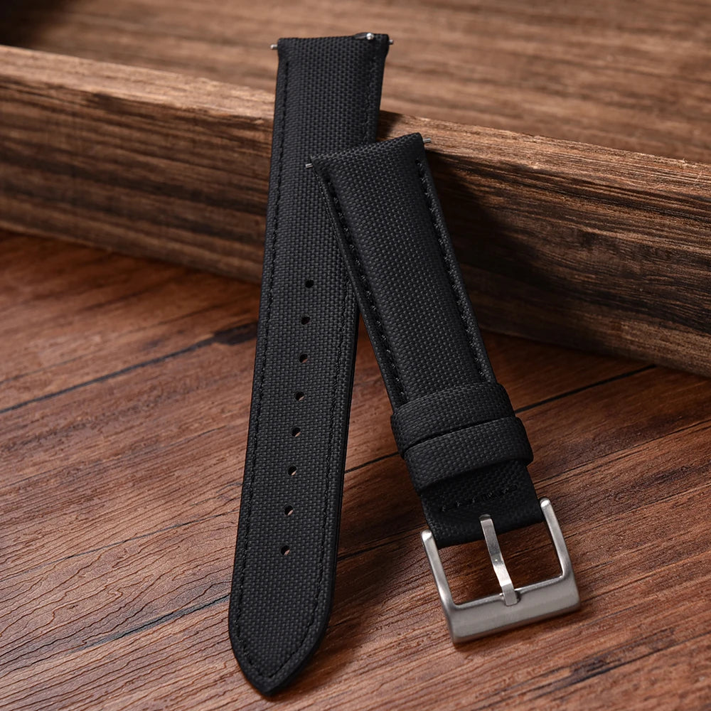 Black watch strap with silver buckle on a wooden surface