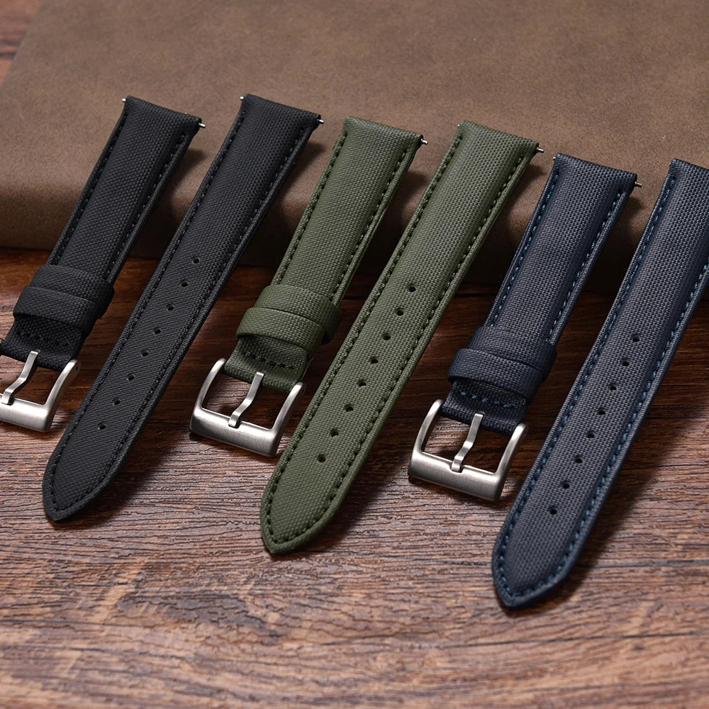Set of four watch straps in black, green, and navy on a wooden surface