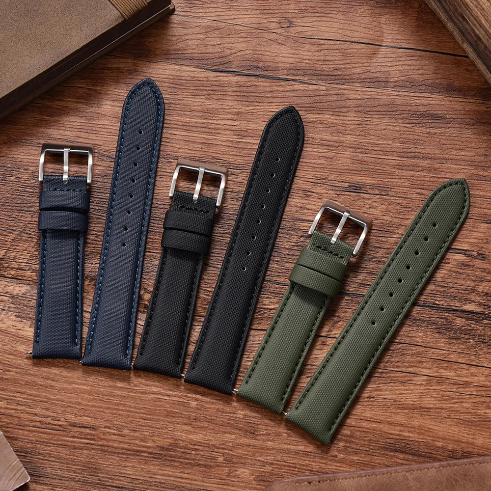 Four watch straps in blue, black, and green on a wooden surface