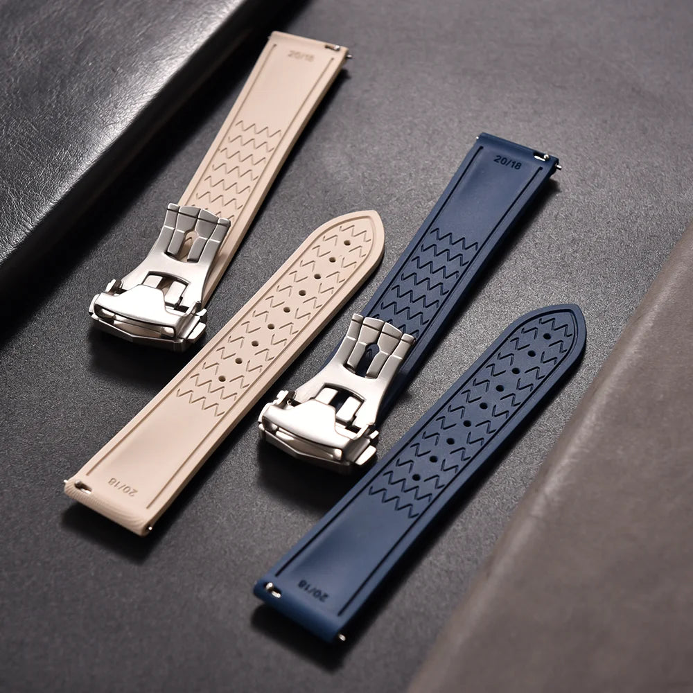 Two watch straps, one beige and one blue, with metallic buckles on a dark surface.