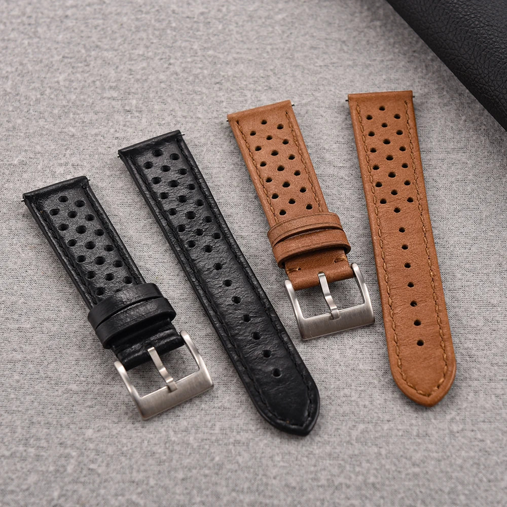 Three leather watch straps in black, brown, and another brown color on a gray surface.