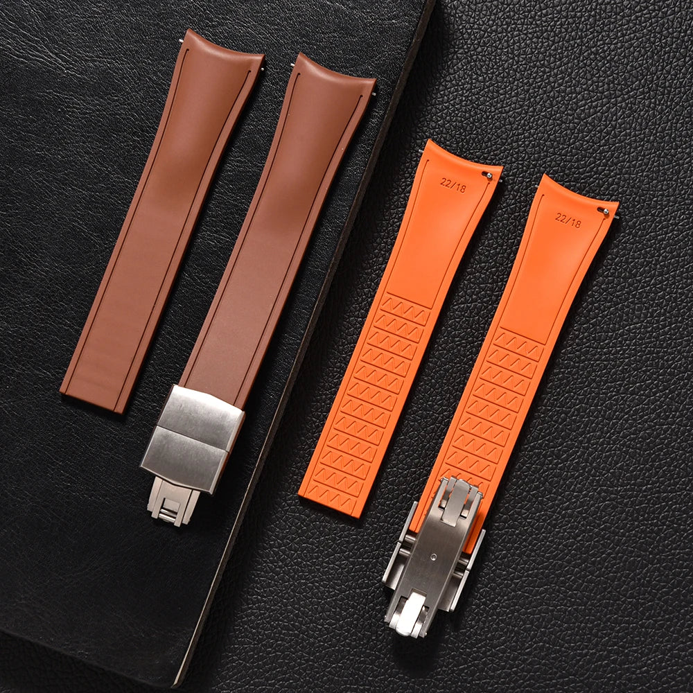 Two brown and two orange watch straps with metal clasps on a black textured background