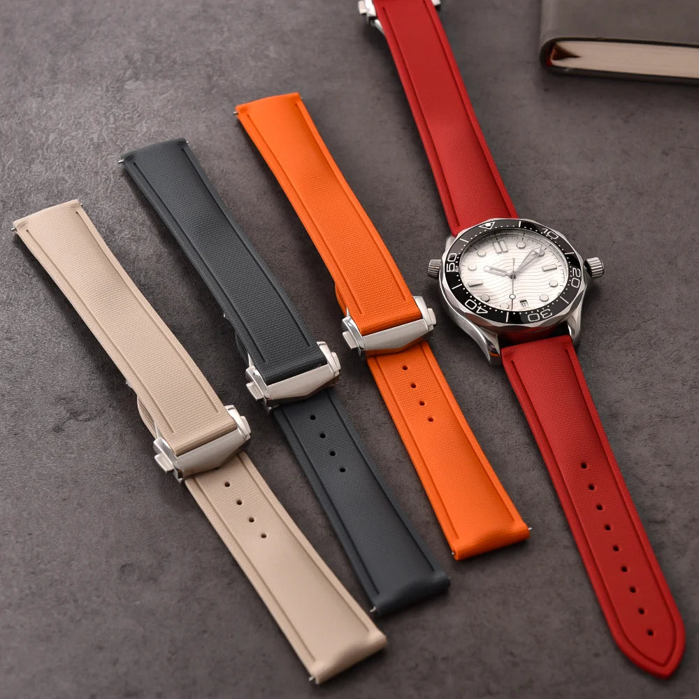 Set of four watch straps in beige, black, orange, and red on a dark surface.
