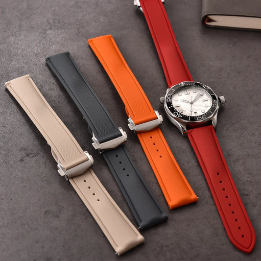 Set of four watch straps in beige, black, orange, and red on a dark surface.