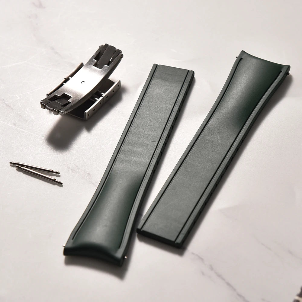 Two green leather straps and a metal component on a white surface