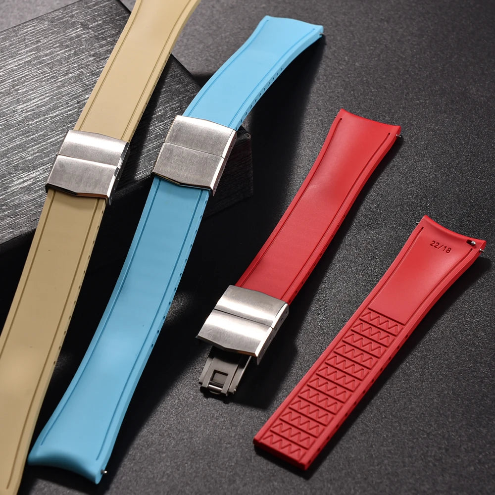 Four watch straps in beige, blue, and red on a dark surface