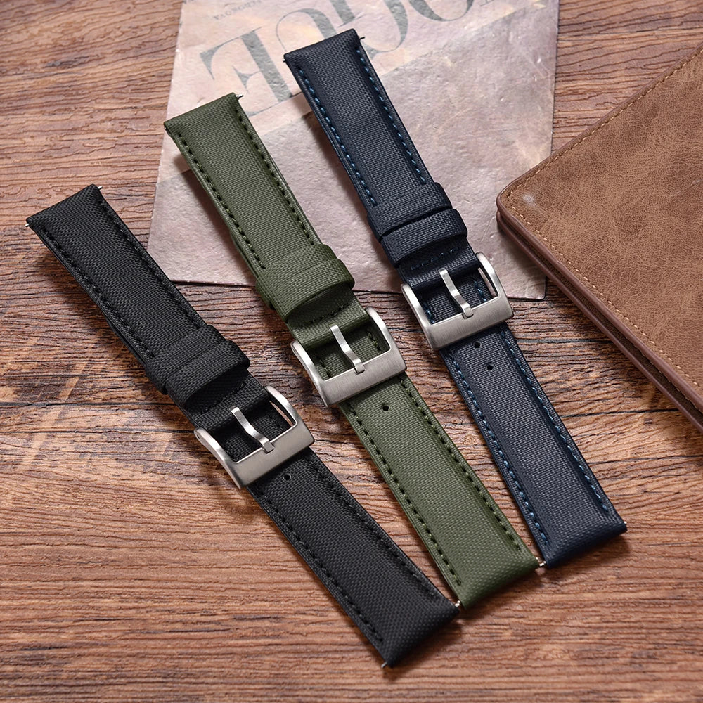 Four watch straps in black, green, and blue on a wooden surface with a newspaper underneath.